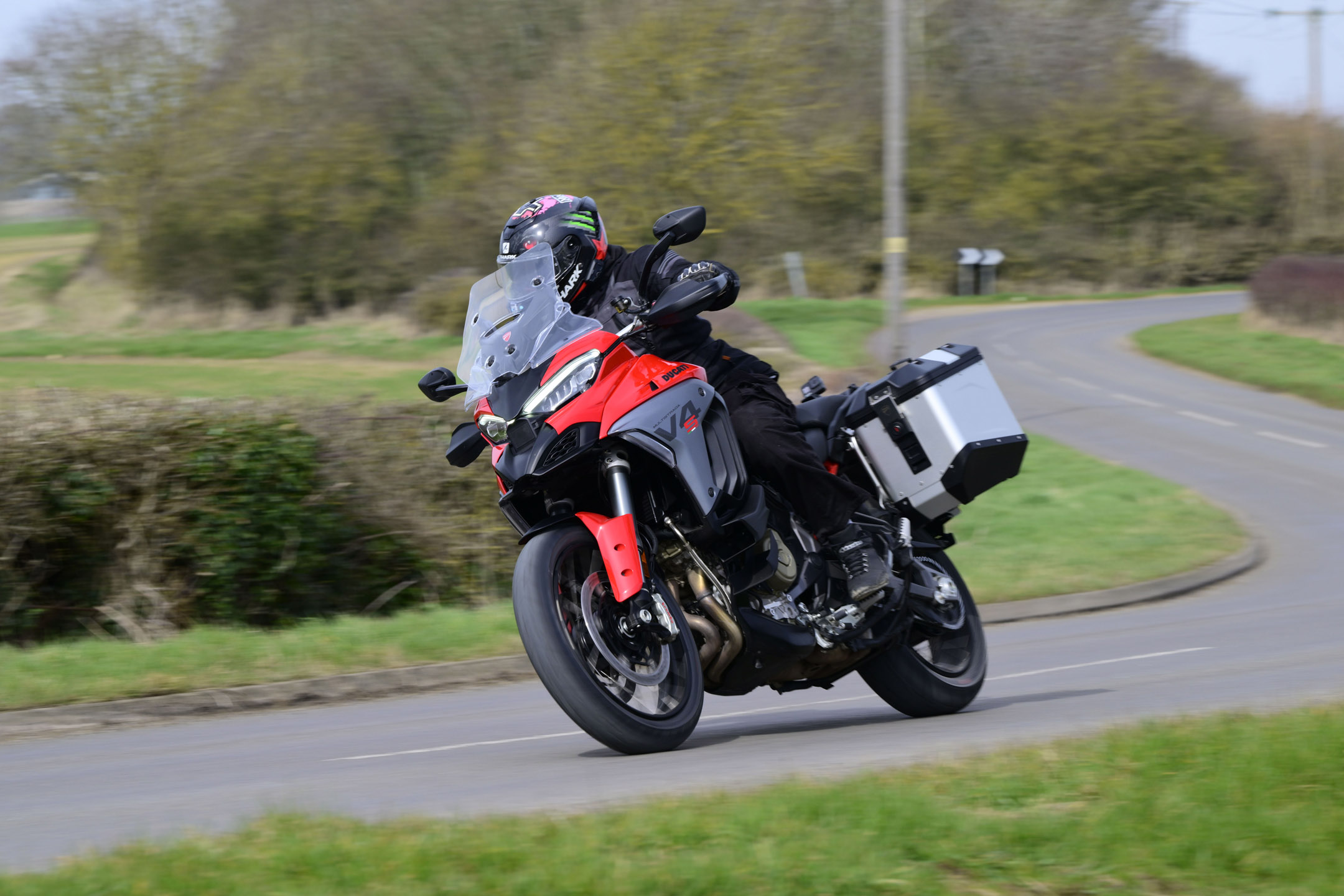 young man riding a red/black/grey Ducati adventure bike on a twisty country road