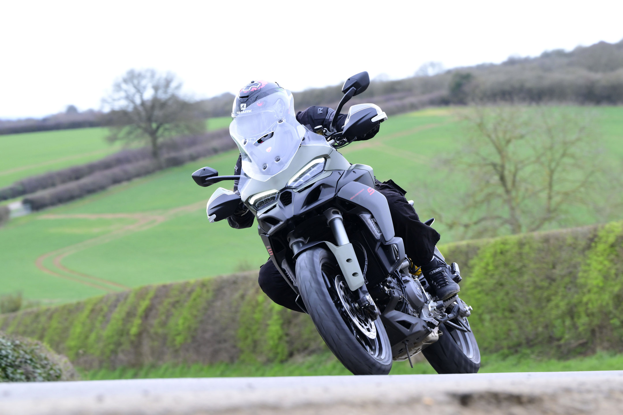 young man riding a black/grey Ducati adventure bike on a country road