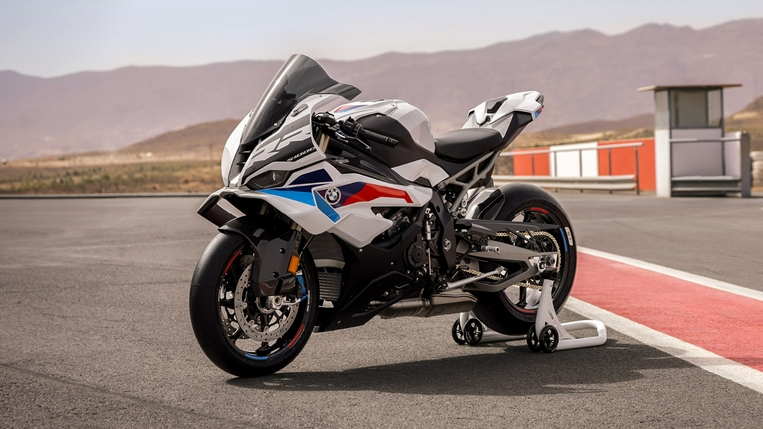 White/blue/red BMW Sports bike parked on a track in Spain.