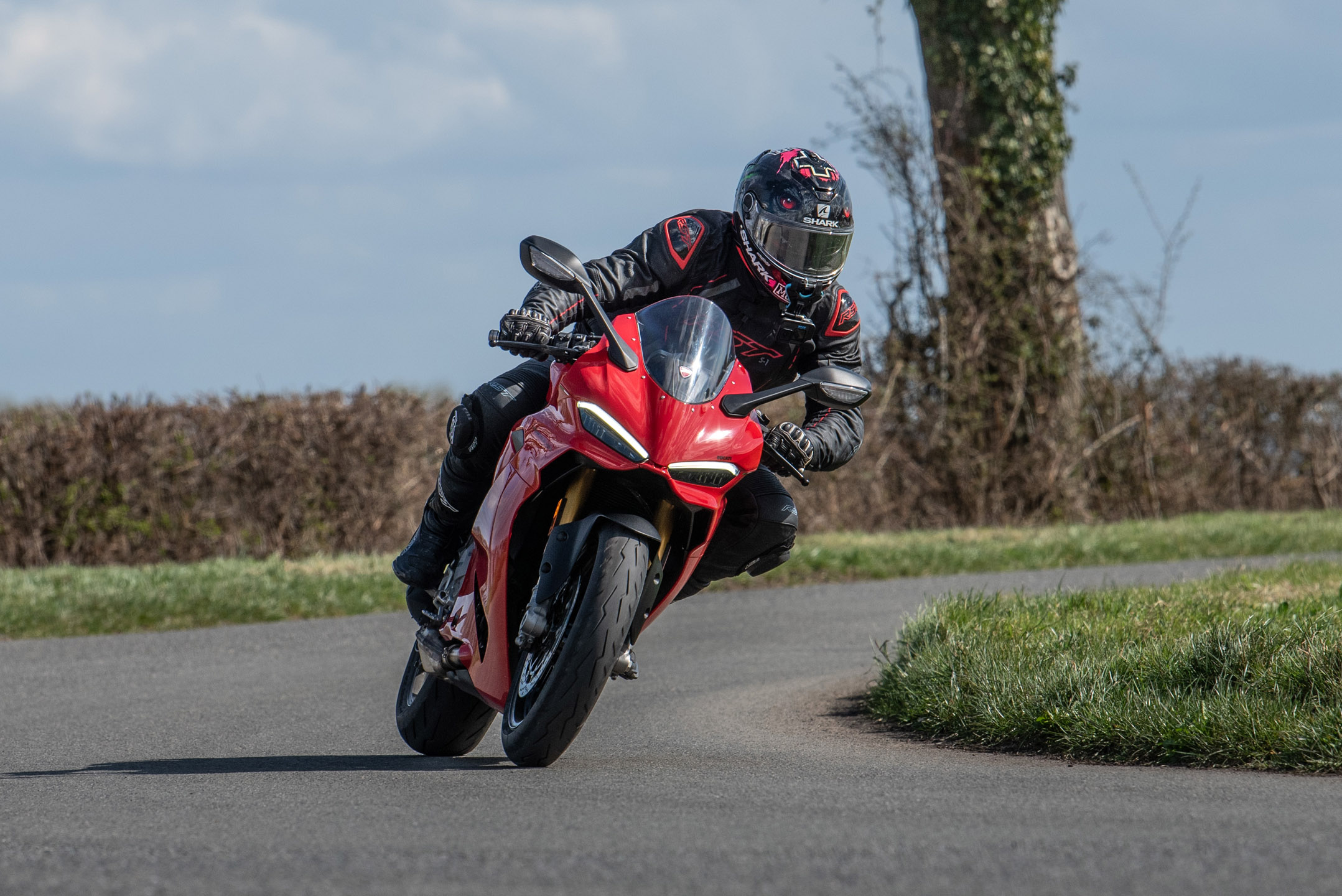 Young man riding a red Ducati sports bike on a country road in Peteborough.