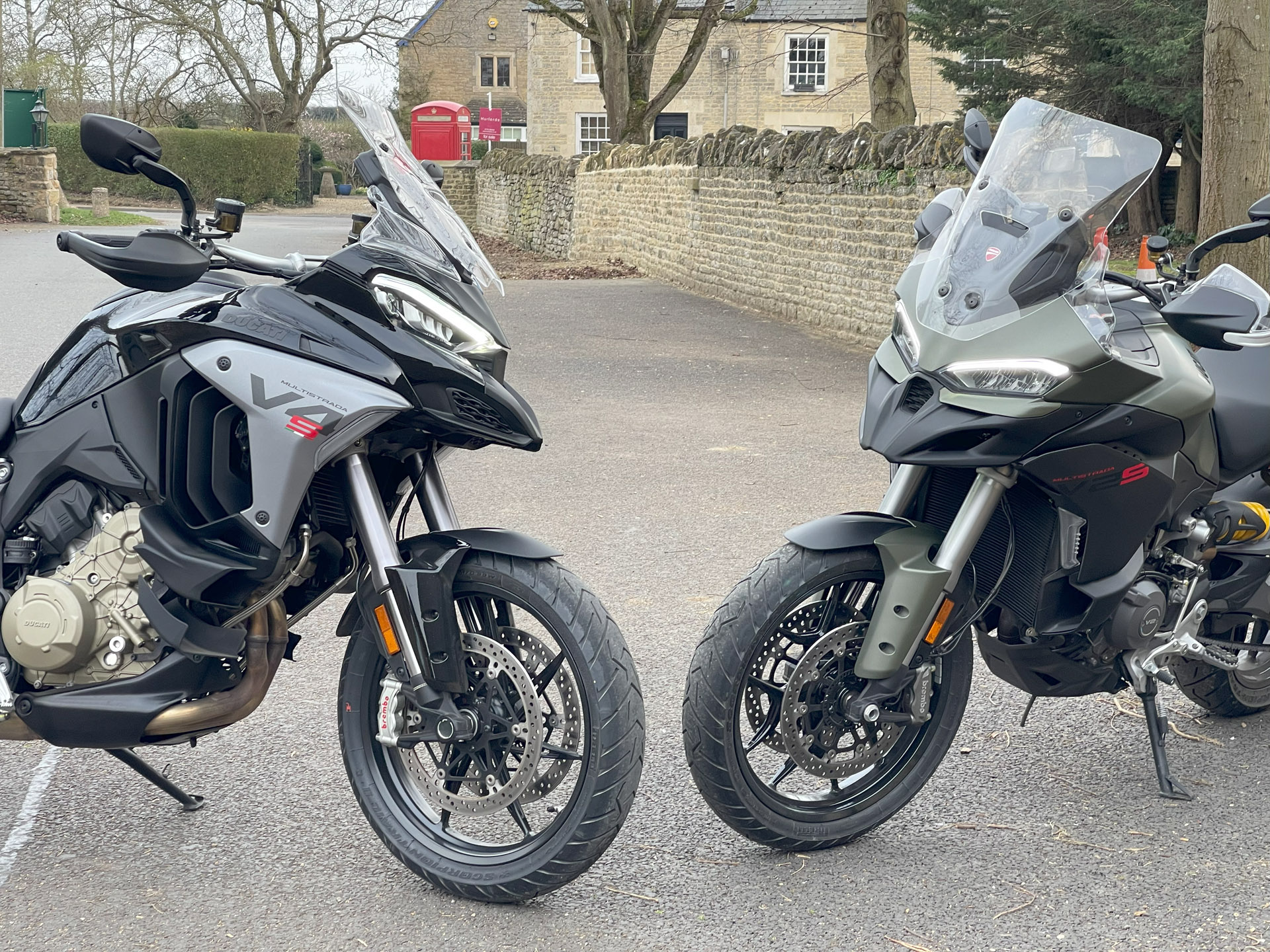 Two black/grey Ducati adventure bikes parked face together in a little British country village
