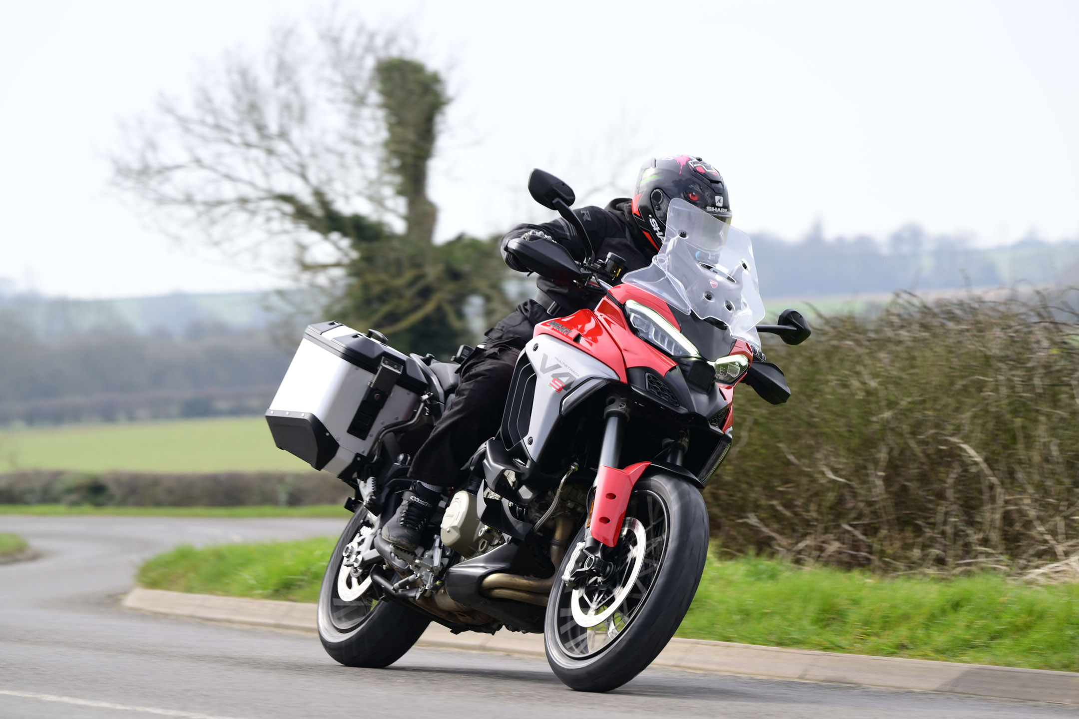 Young man riding the red/black Ducati Multistrada adventure motorbike on a country road
