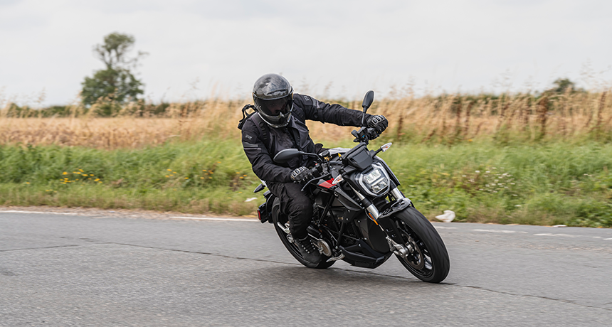 a person turning a corner on a scooter, next to a field