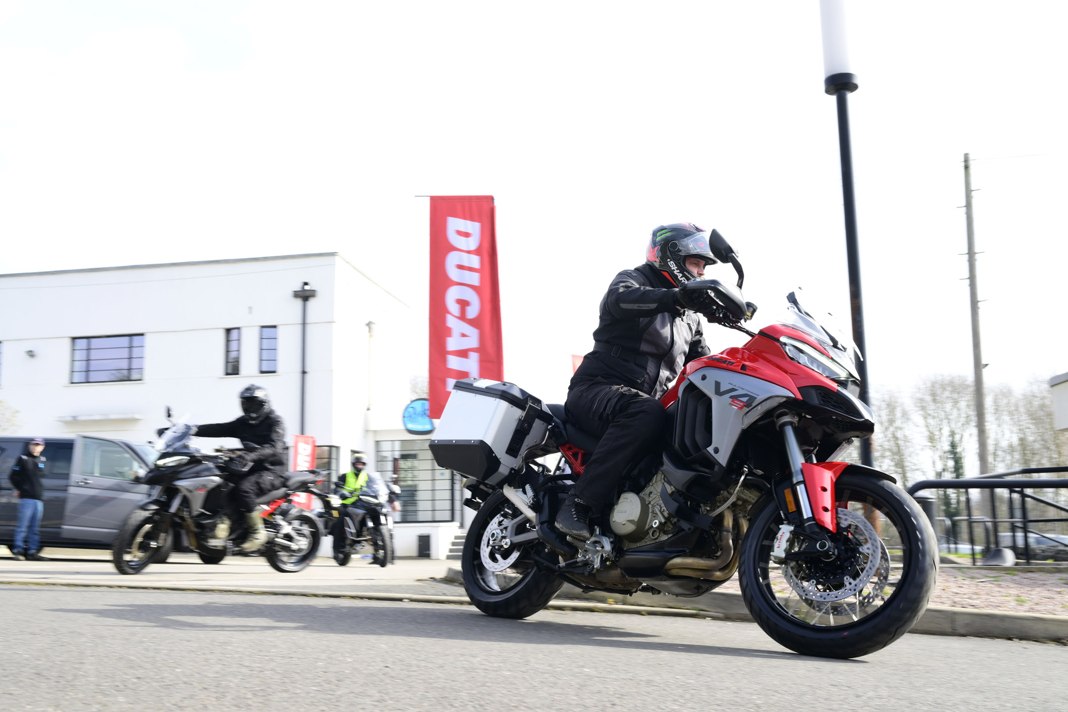 Young man riding a red/black Ducati adventure bike through a city 
