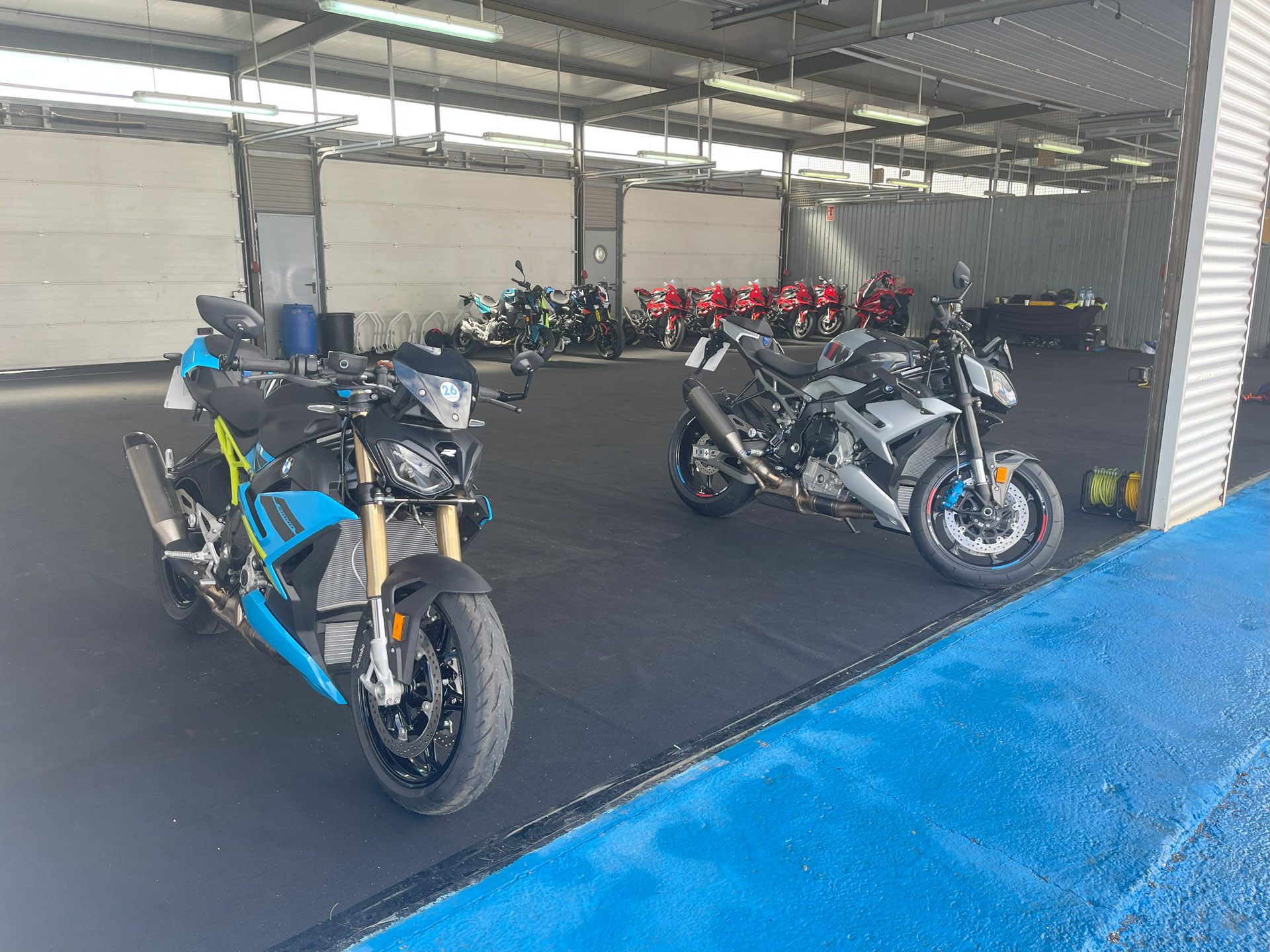 Two BMW sports bikes parked up in the pit lane garage