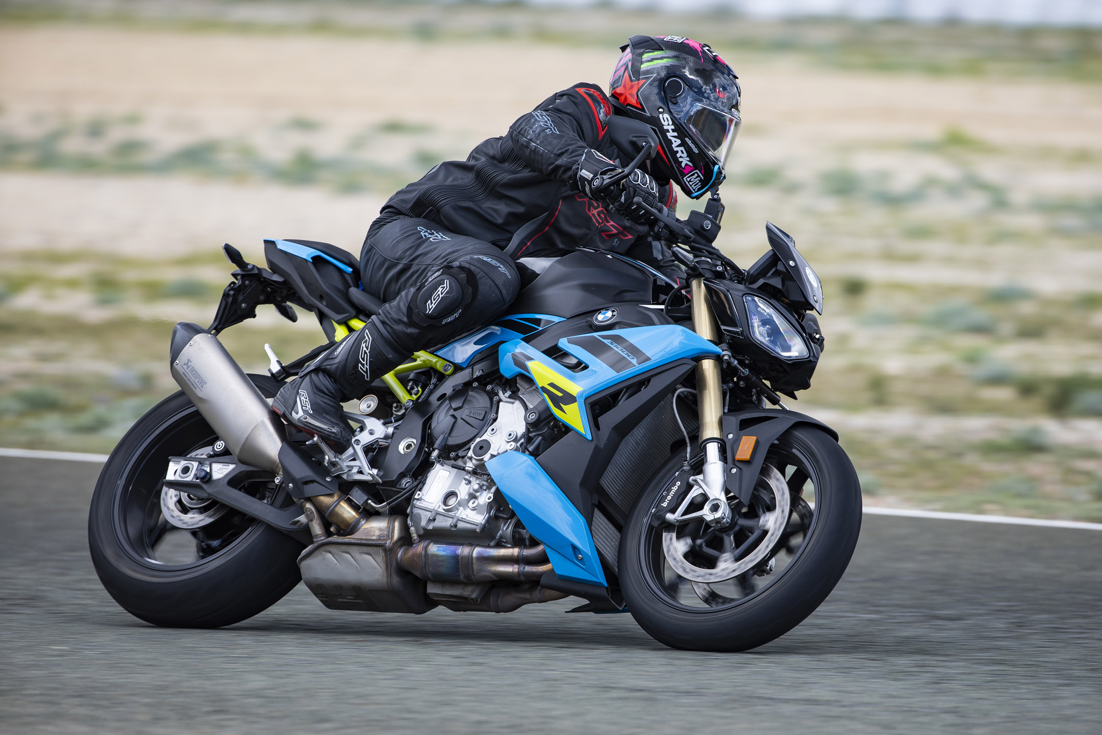 Young man riding a blue/black BMW naked sport motorcycle around a racetrack in Spain
