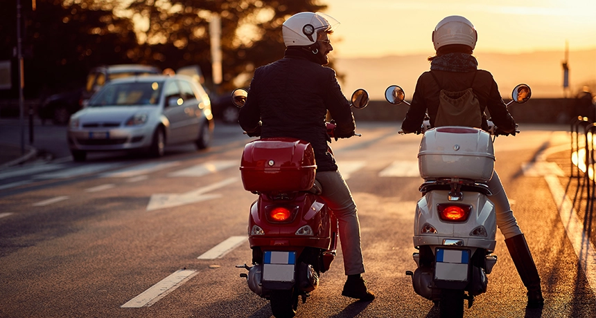Two people riding on scooters