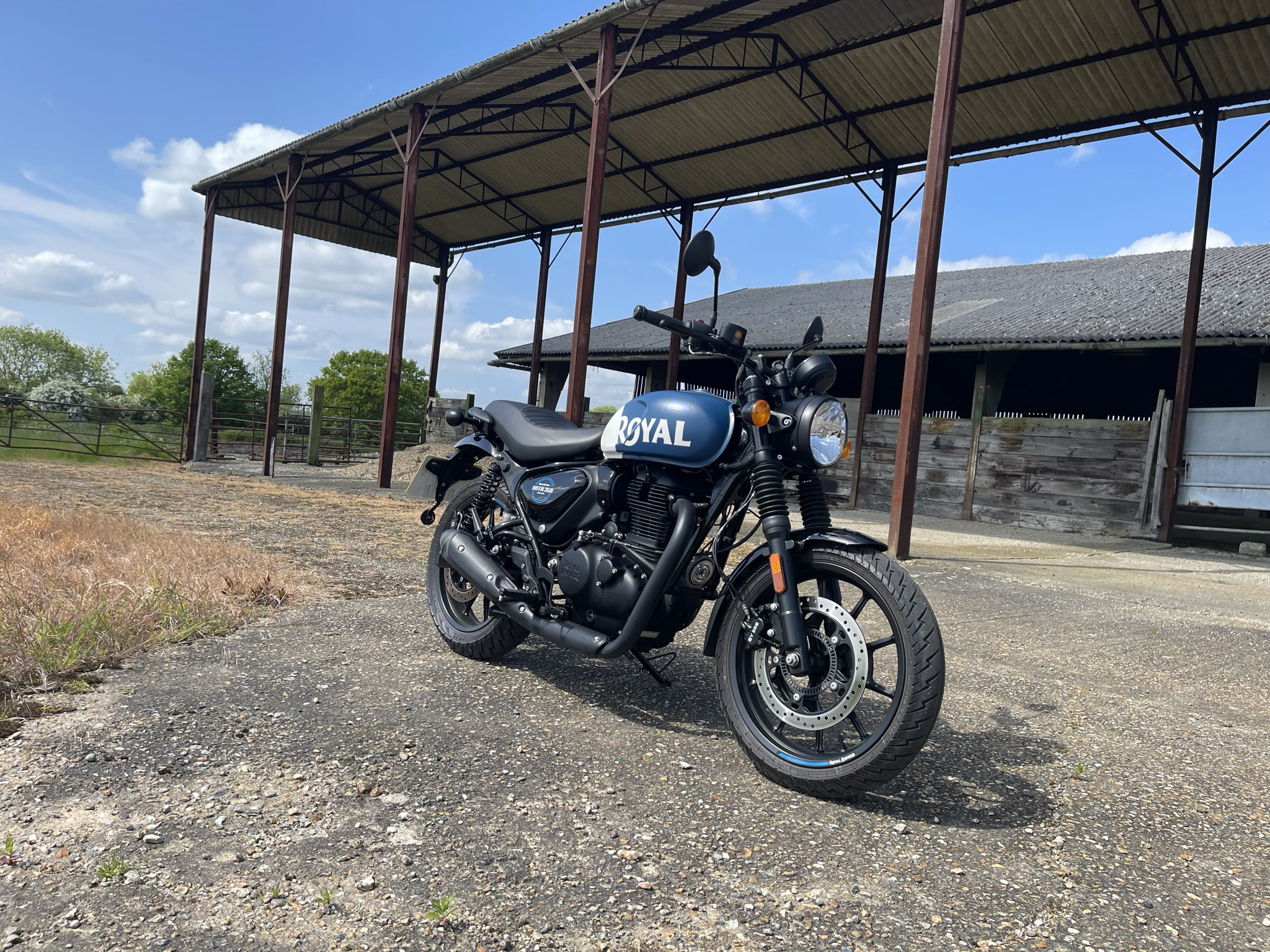 Royal Enfield Hunter 350 in Rebel Blue in front of industrial background