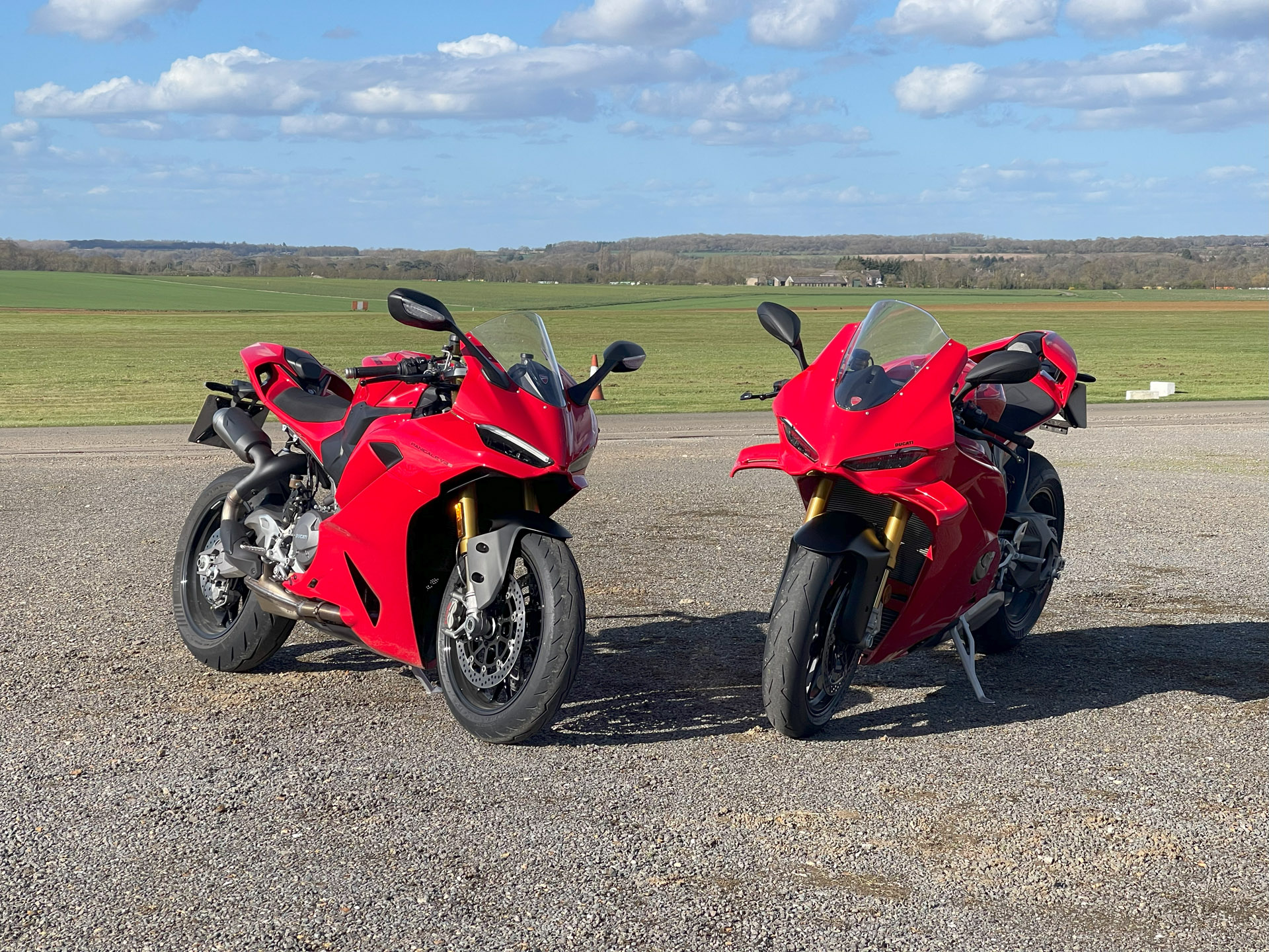 Two red/black Ducati sportsbikes parked in front of a green grass field