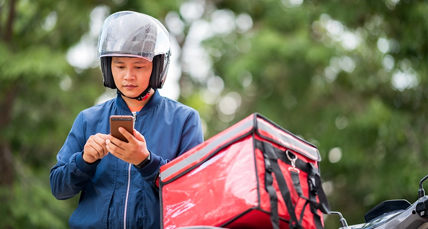 Delivery rider checks phone for deliveries